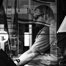 A tram driver in his cab with multiple reflections on the windows on Picardy Place, Edinburgh
