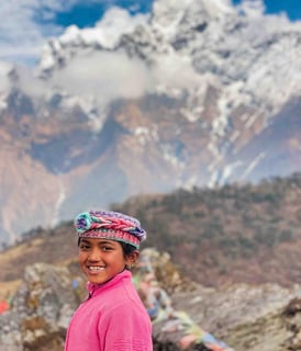 Portrait of a young Nepali girl with a snow-covered peak in the background.