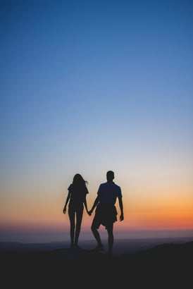 a couple holding hands while standing on a hill
