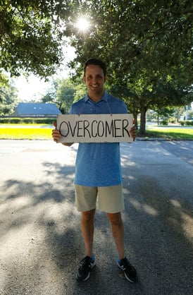 A transformed man holding a overcomer sign