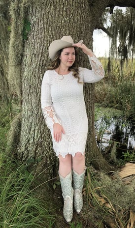 a woman in a white dress and cowboy boots