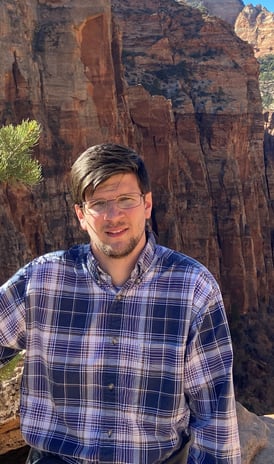 a man standing on a mountain top with a mountain in the background