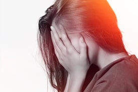 mulher com ansiedade com as mãos no rosto sem saber o que pensar