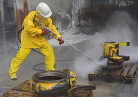 Un homme en imperméable jaune utilise un nettoyeur à pression.
