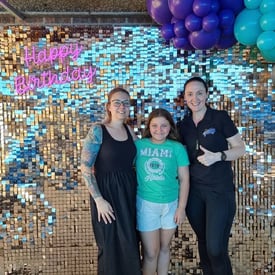 Violet and her mum in front of the rose gold shimmer wall and neon sign in Redlands.