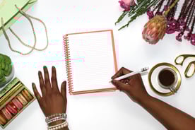a woman's hands holding a notebook and writing on a notebook