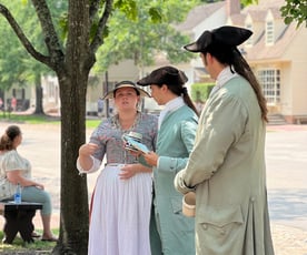 Colonial villagers in Williamsburg stood in the street chatting.