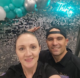 Carly and Kahn from SweetAz Co. taking a selfie in front of the silver shimmer wall, Thirty neon sign, and balloon garland fo