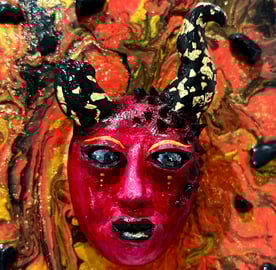 Un visage sculptée rouge avec des cornes dont une cassée