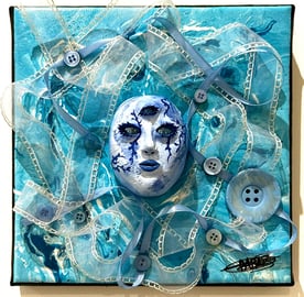 une sculpture d'un visage bleu avec trois yeux et du tissu autour