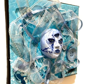 une sculpture d'un visage bleu avec trois yeux et du tissu autour