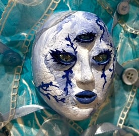 une sculpture d'un visage bleu avec trois yeux et du tissu autour