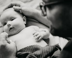 Papa protège tendrement son bébé avec ses mains – photo naissance à domicile dans le Gard