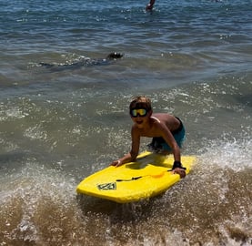 Boy on a boogie board next to a seal in Kauai