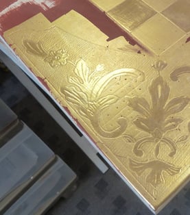 Détail de la pose de dorure à la feuille d'or pour le décor d'un échiquier.