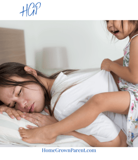 Mother in bed exhausted with small daughter on her back