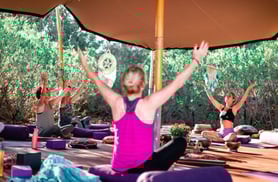 a woman in a pink tank top and black pants doing yoga