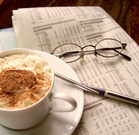 Cappuccino with pen, newspaper and glasses