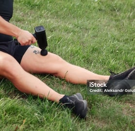 a man with tattoos on his leg using massage gun
