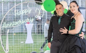 Carly and Kahn from SweetAz Co. in front of a circle backdrop with a Happy 20th Anniversary sign at home in Redlands.
