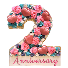 Cookie cake decorated with chocolate buttercream, topped with assorted chocolates and French macarons for celebrations