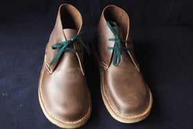 a pair of brown shoes with green laces