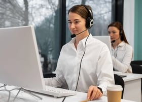 a woman in a white shirt and headphones on a computer
