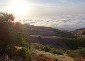 a mountain view of a valley with clouds