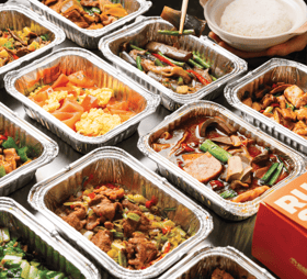 a table with many trays of food and a person holding a spoon