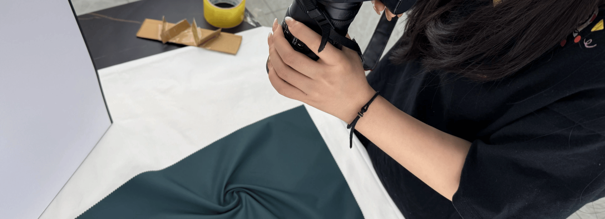 Photographer shooting YL fabric in deep blue velvet on a white table with a DSLR camera.