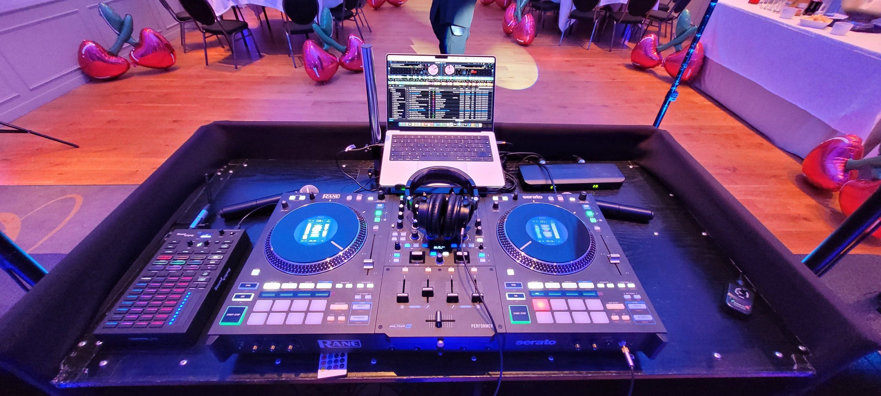 Professional Rane DJ controller setup with laptop and headphones at a party venue with cherry balloons.