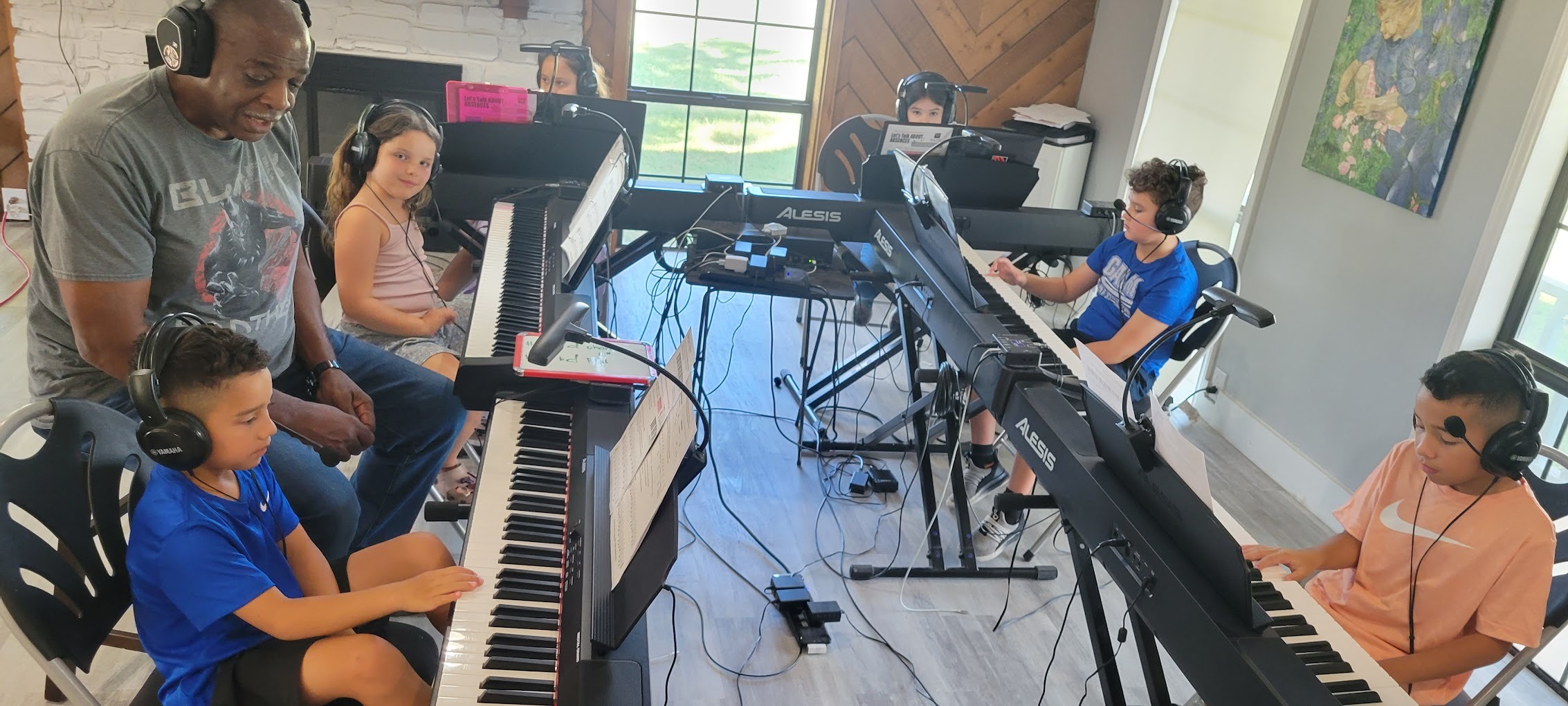 a group of kids sitting at pianos with a teacher