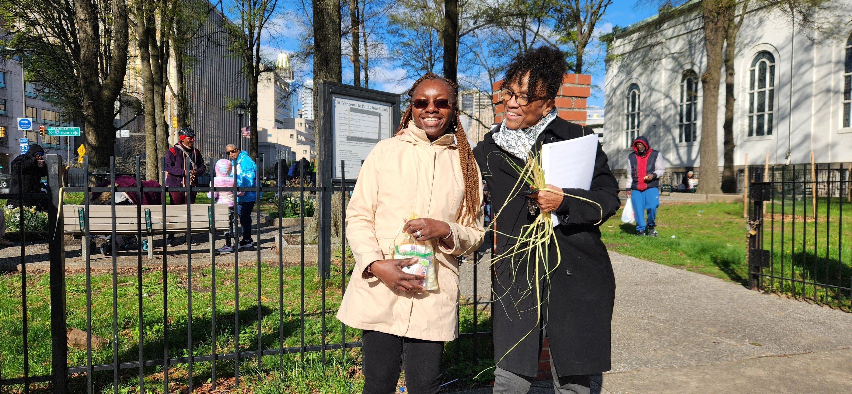 two people standing in front of a fence holding hygiene kits