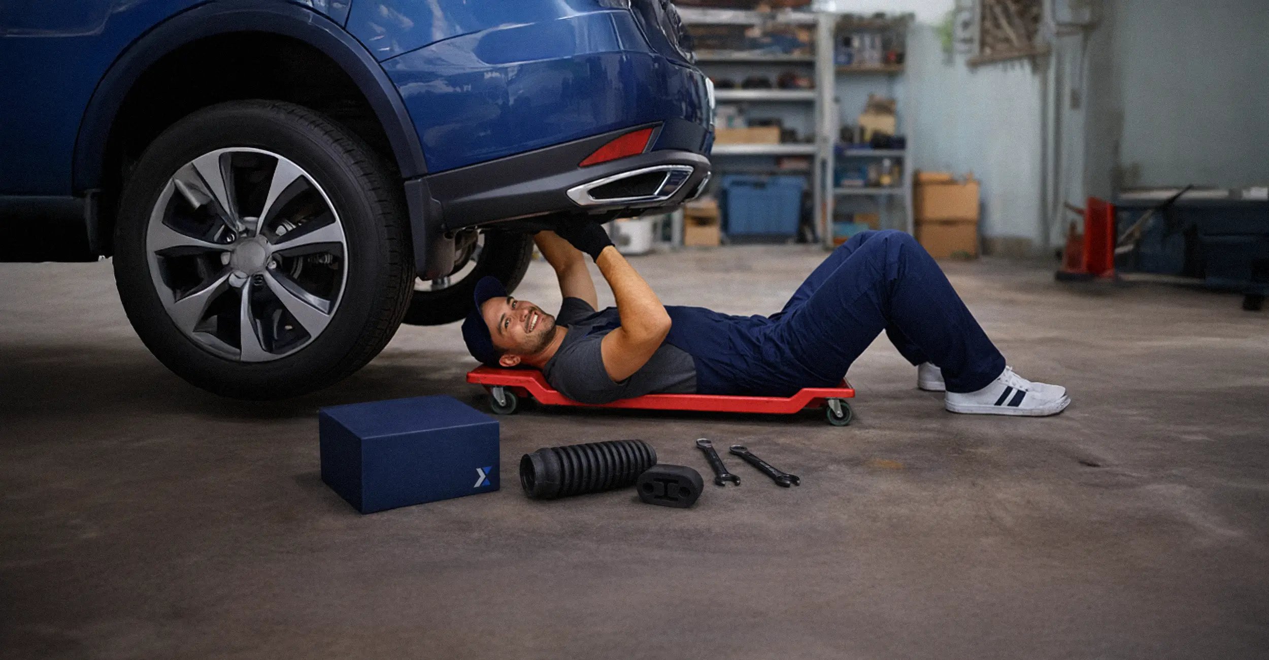 Meccanico sotto l’auto con scatola Hulemex, esempio di packaging coordinato e branding consapevole.