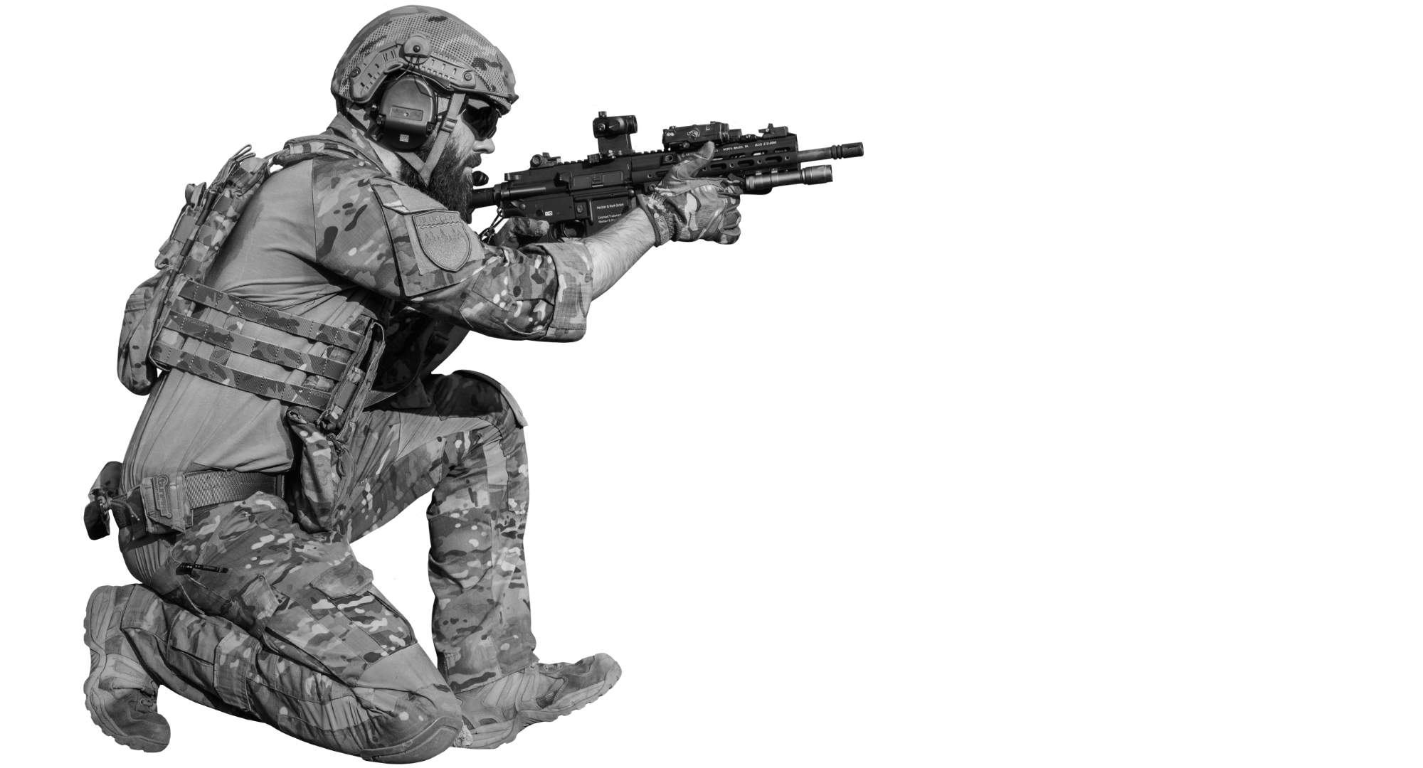 Profesionalus airsofto žaidėjas su pilna taktine ekipuote klūpi ir taikosi su moderniu šratasvydžio 