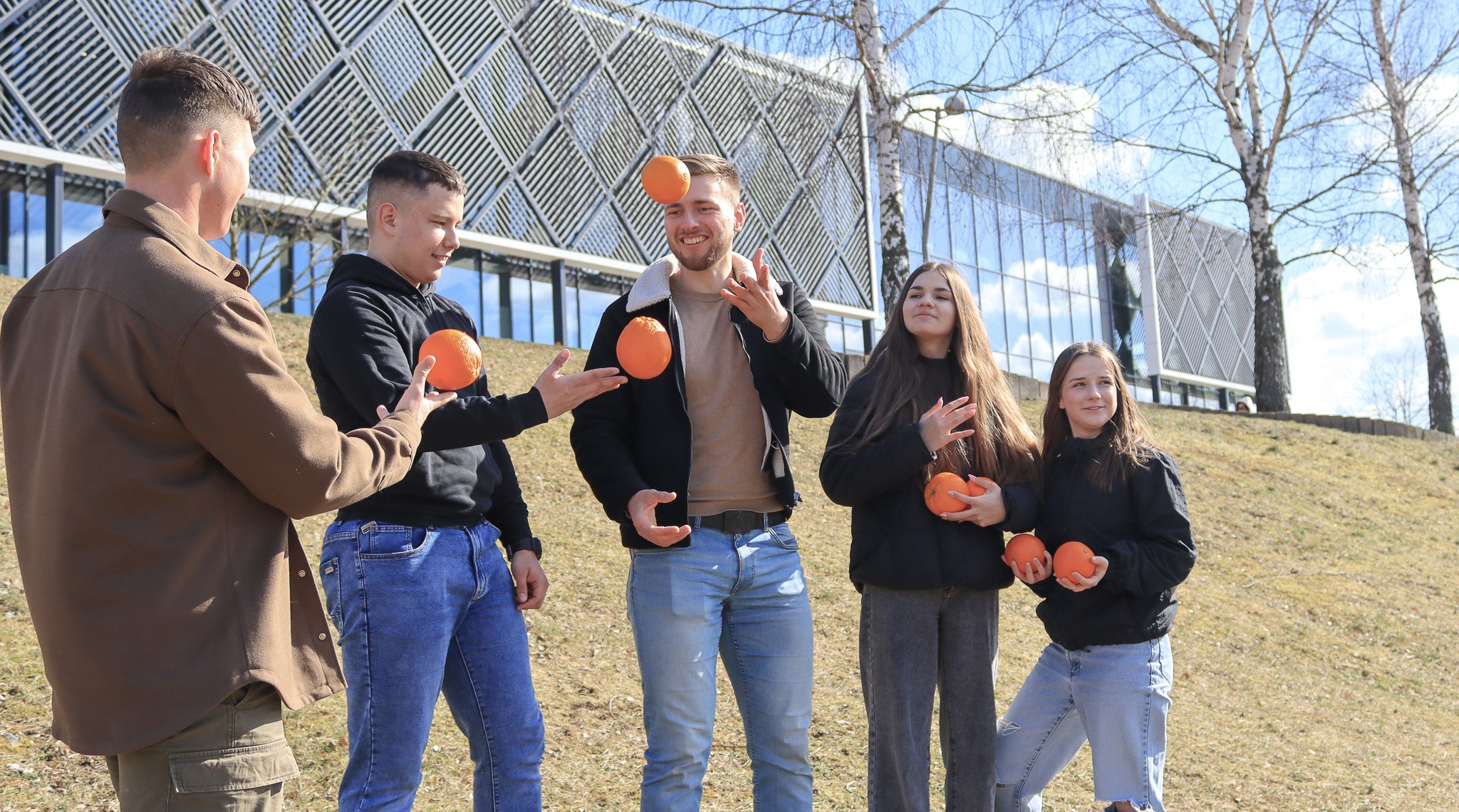 Jauni zmones lauke zaidzia su apelsinais