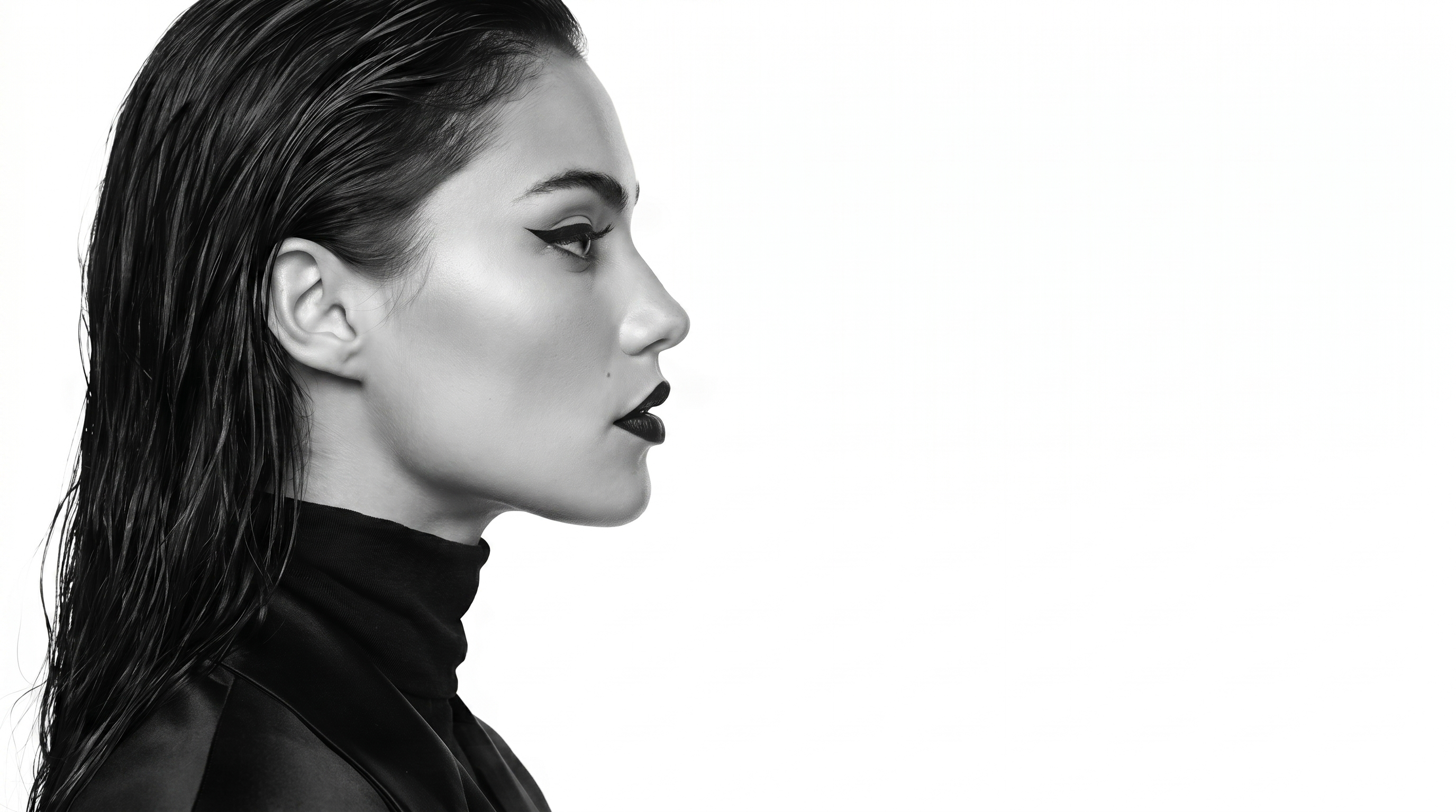 Side profile of a woman with wet hair, bold winged eyeliner, and dark lipstick against a white background.