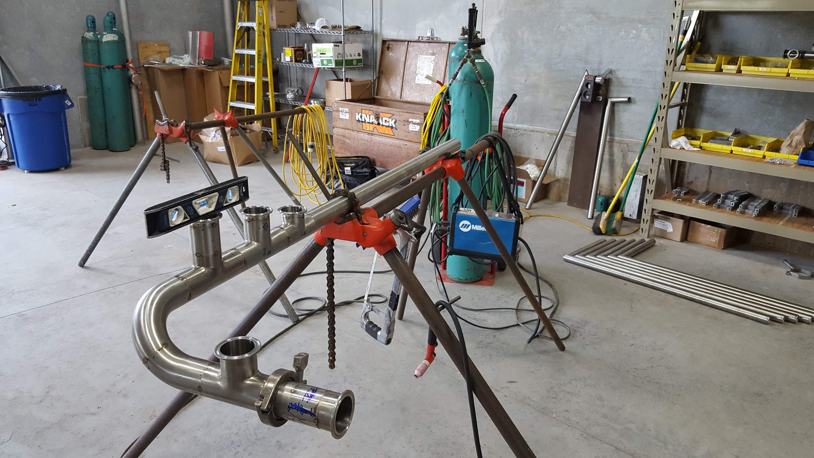 Custom stainless steel pipefitting on a welding stand in an industrial workshop.