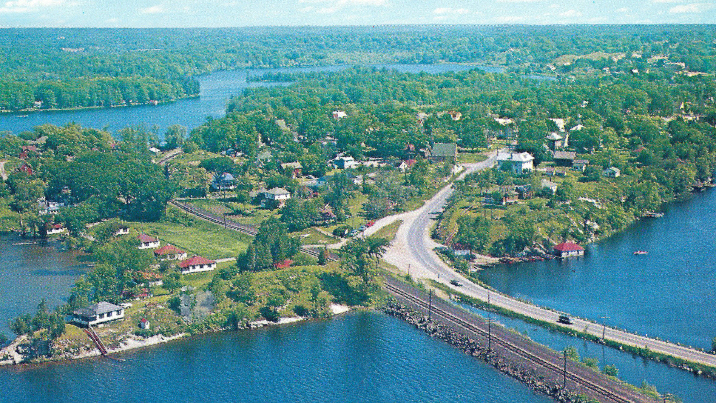 Aerial view of Thousand Islands landscape with lush islands, blue river water, and coastal roads.