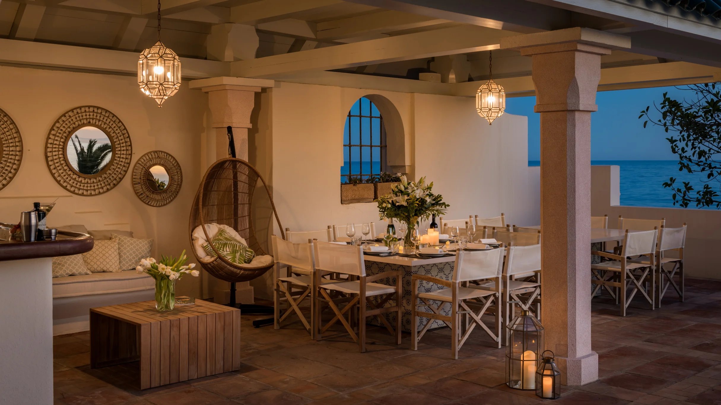 Covered outdoor dining terrace with lantern lighting and sea views