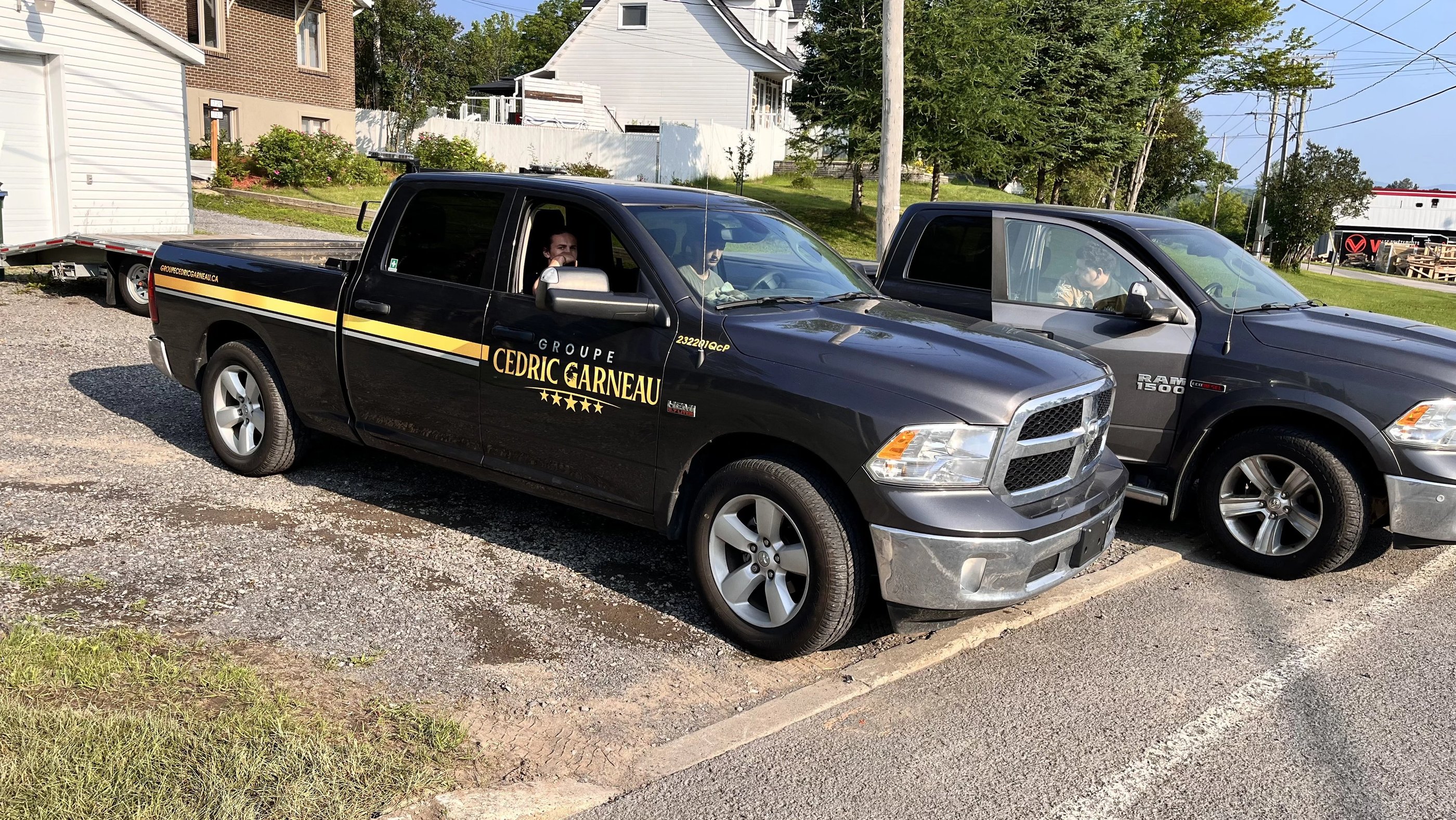 A black Groupe Cedric Garneau Ram 1500 work truck parked on a gravel lot.