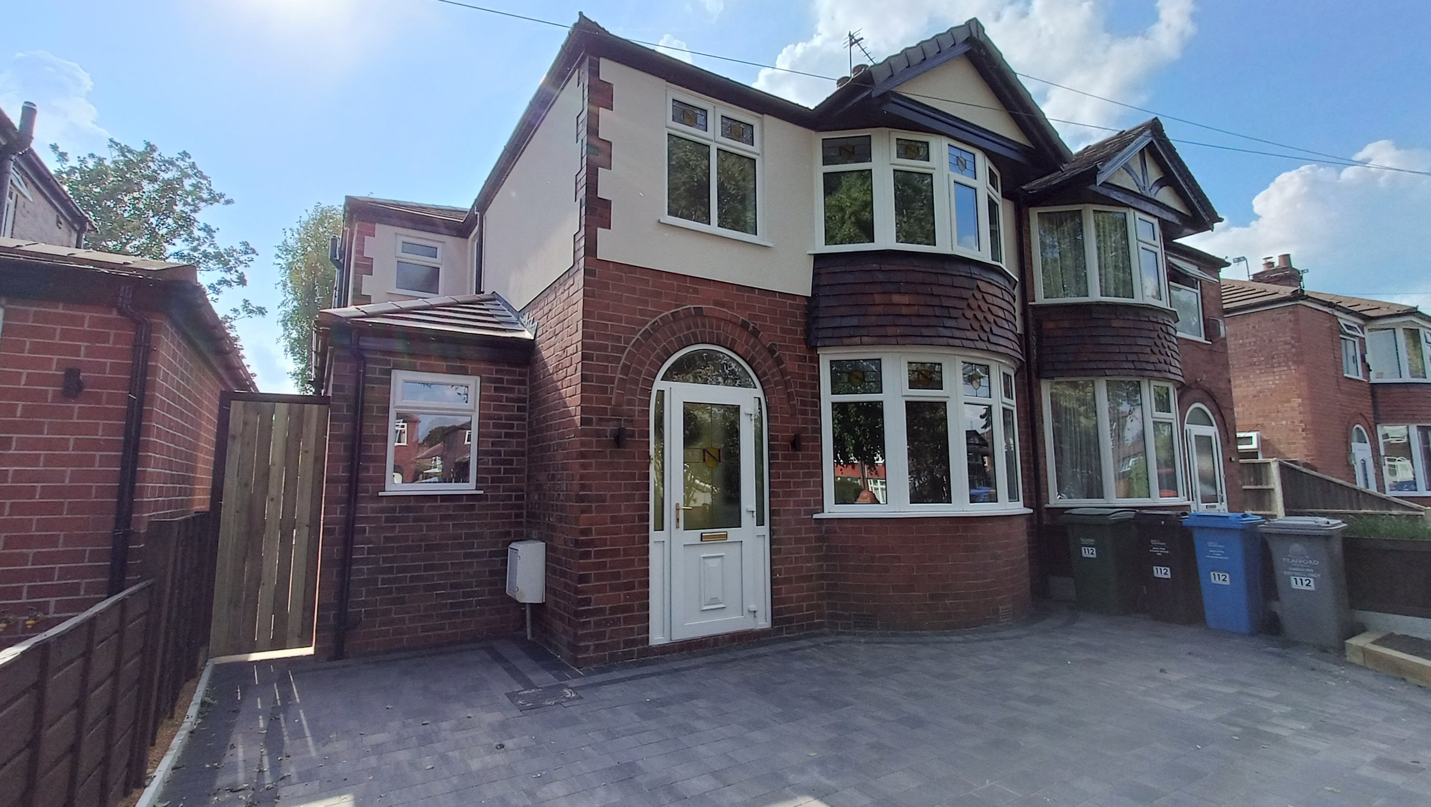 A renovated semi-detached red brick house featuring a modern paved driveway and white uPVC bay windows.