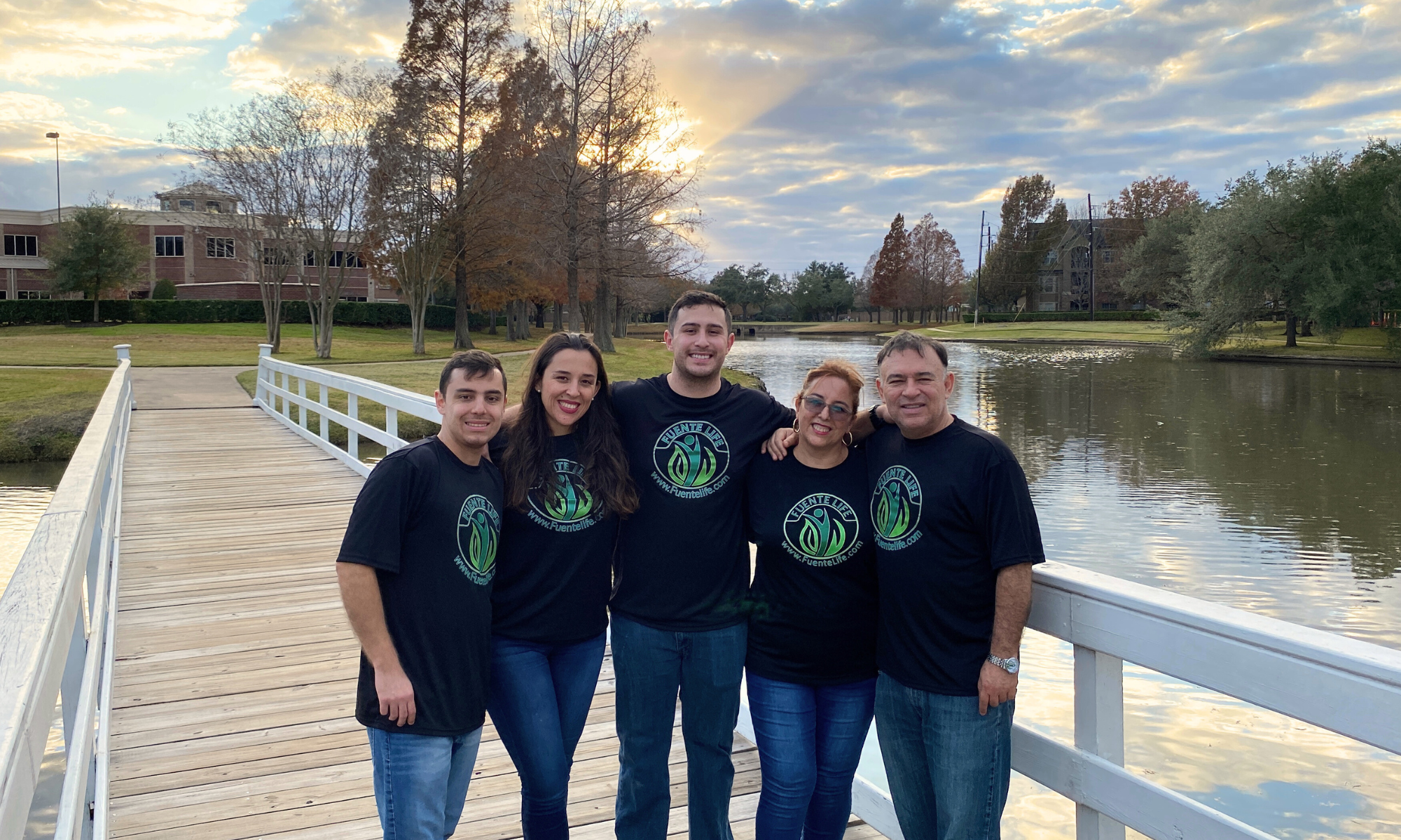 Fuente Life family founders standing together outdoors wearing branded shirts.