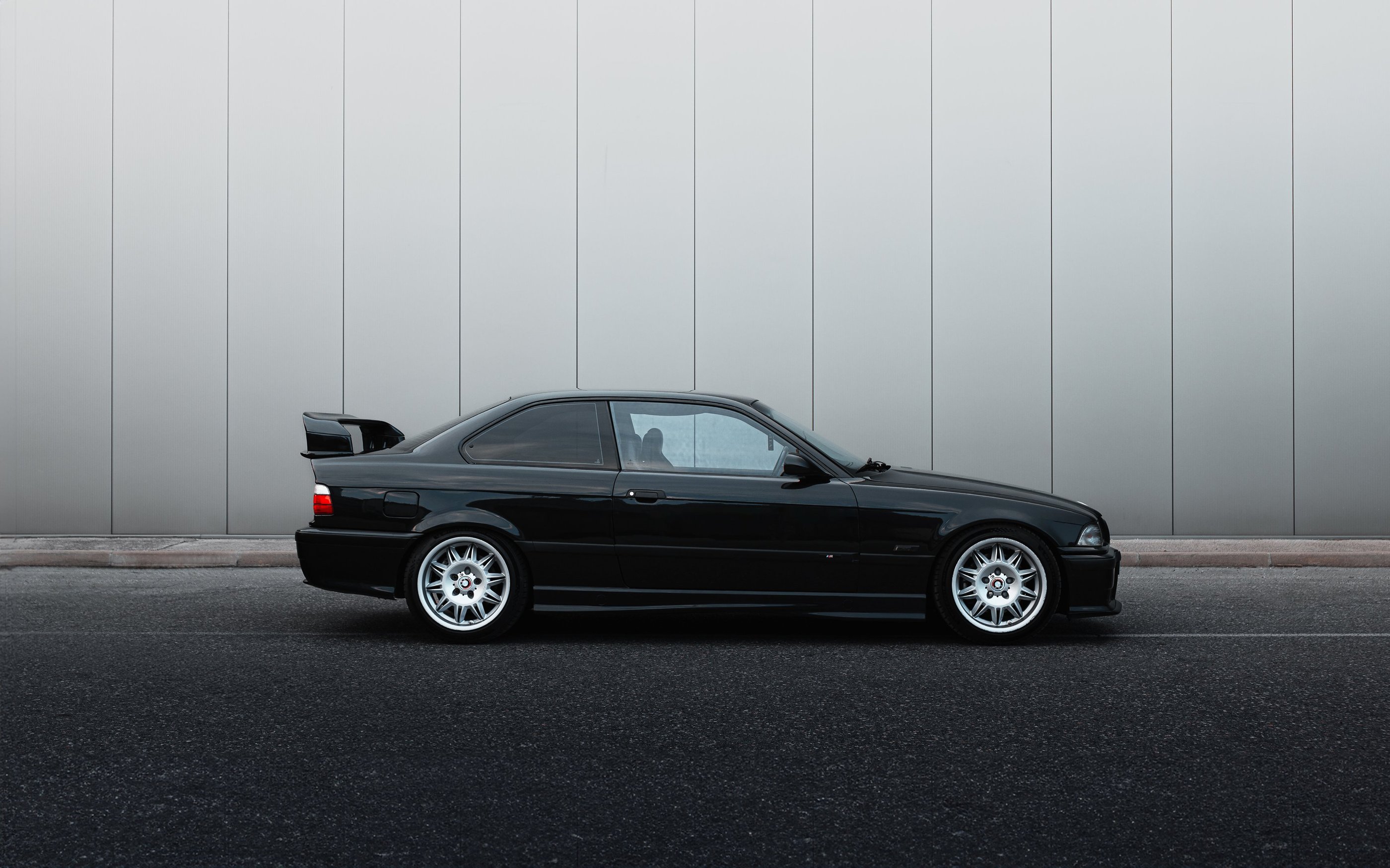 a black bmw m3 e36 parked in front of a building