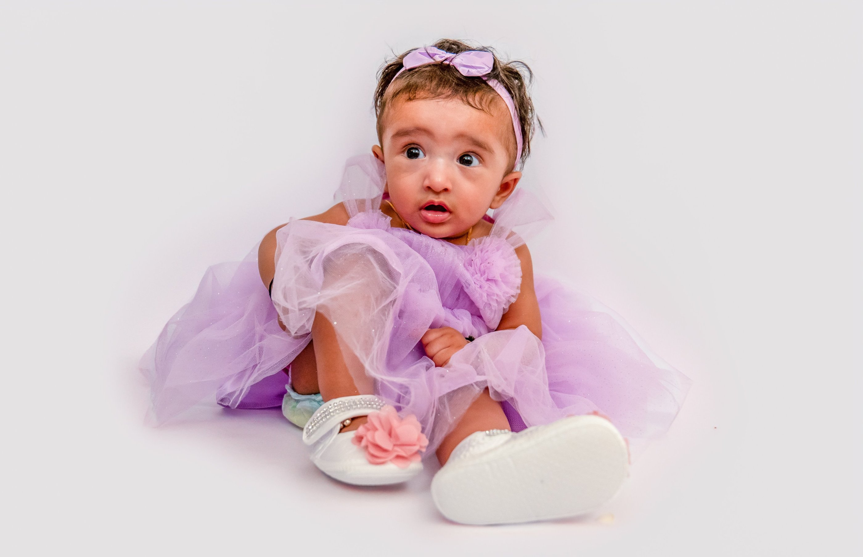 a baby girl in a purple dress and white shoes