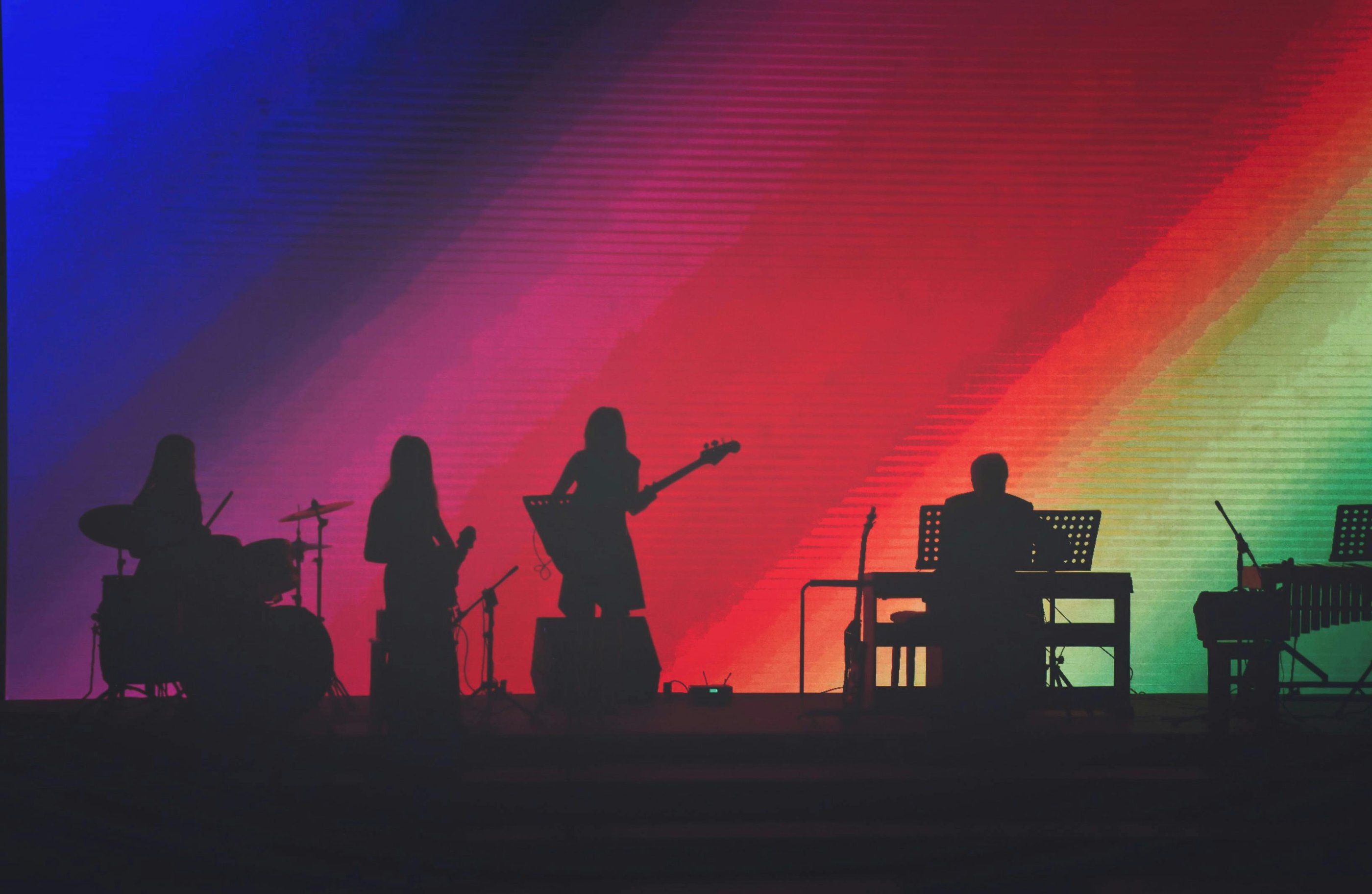 band on stage with rainbow background on screen