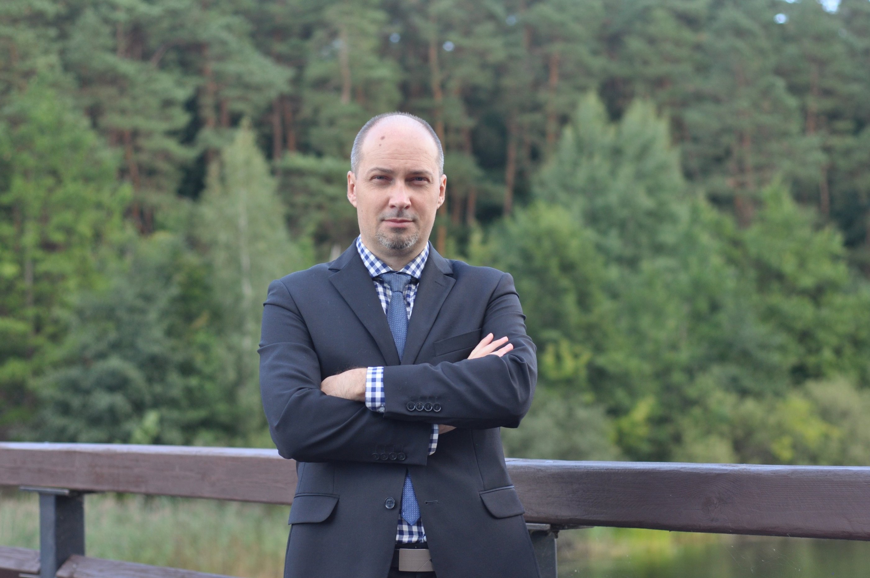 a man in a suit and tie standing on a bridge
