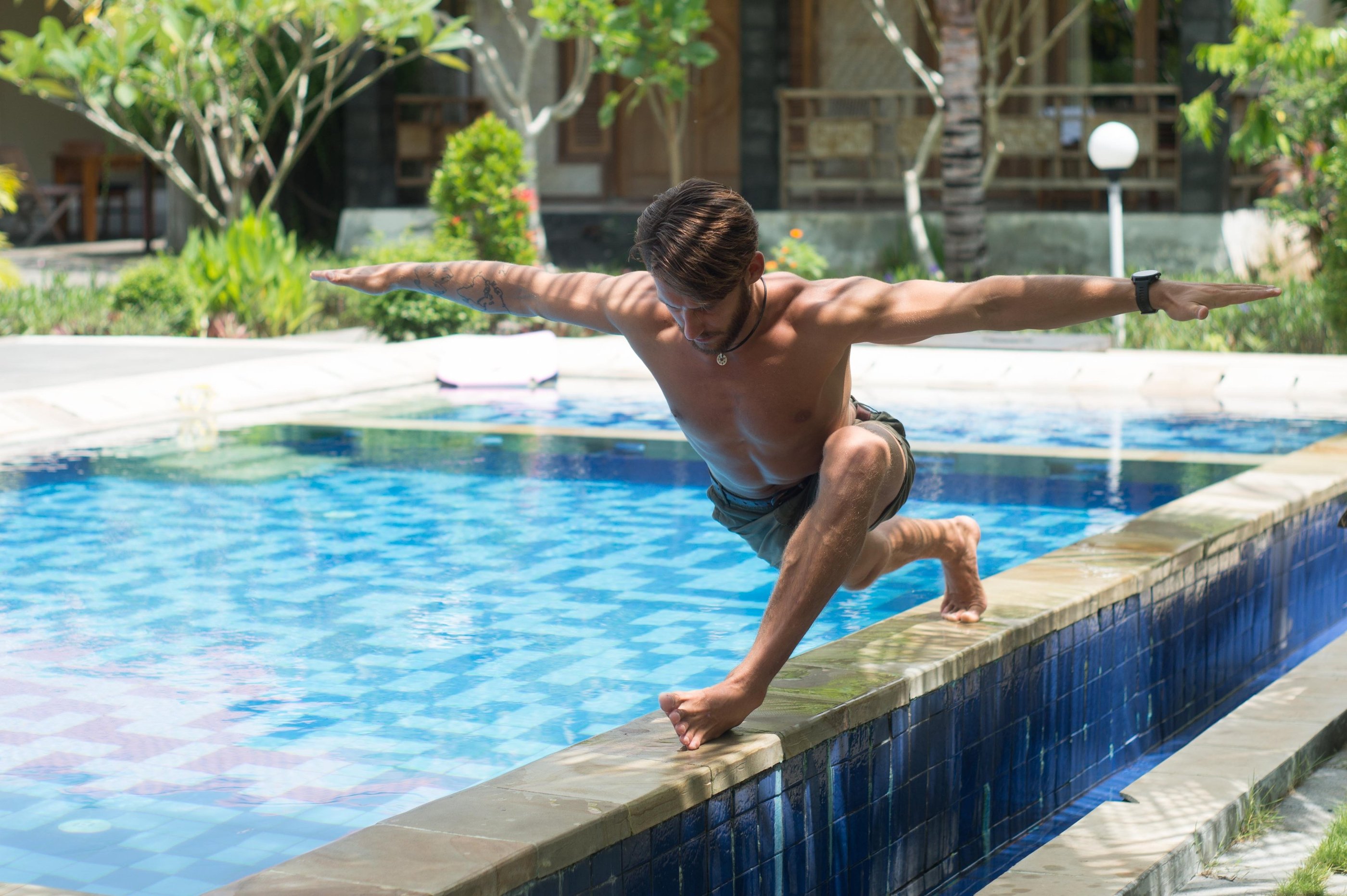 a man is doing a yoga pose on a pool side