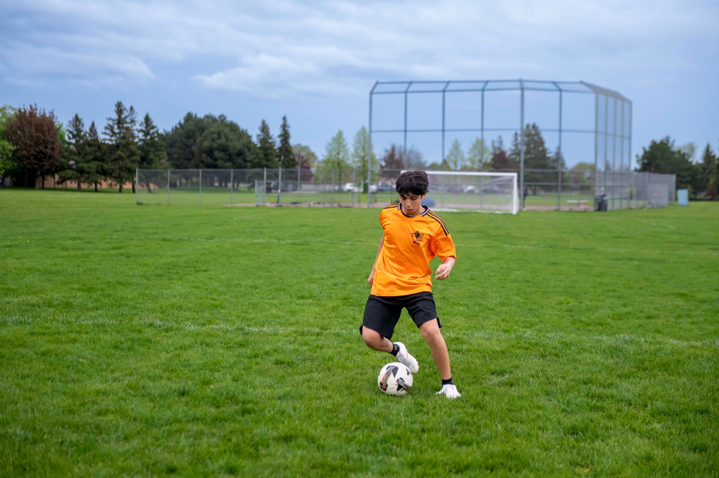Young male soccer MVB FC student dribbling a ball on a green grass in Mississauga