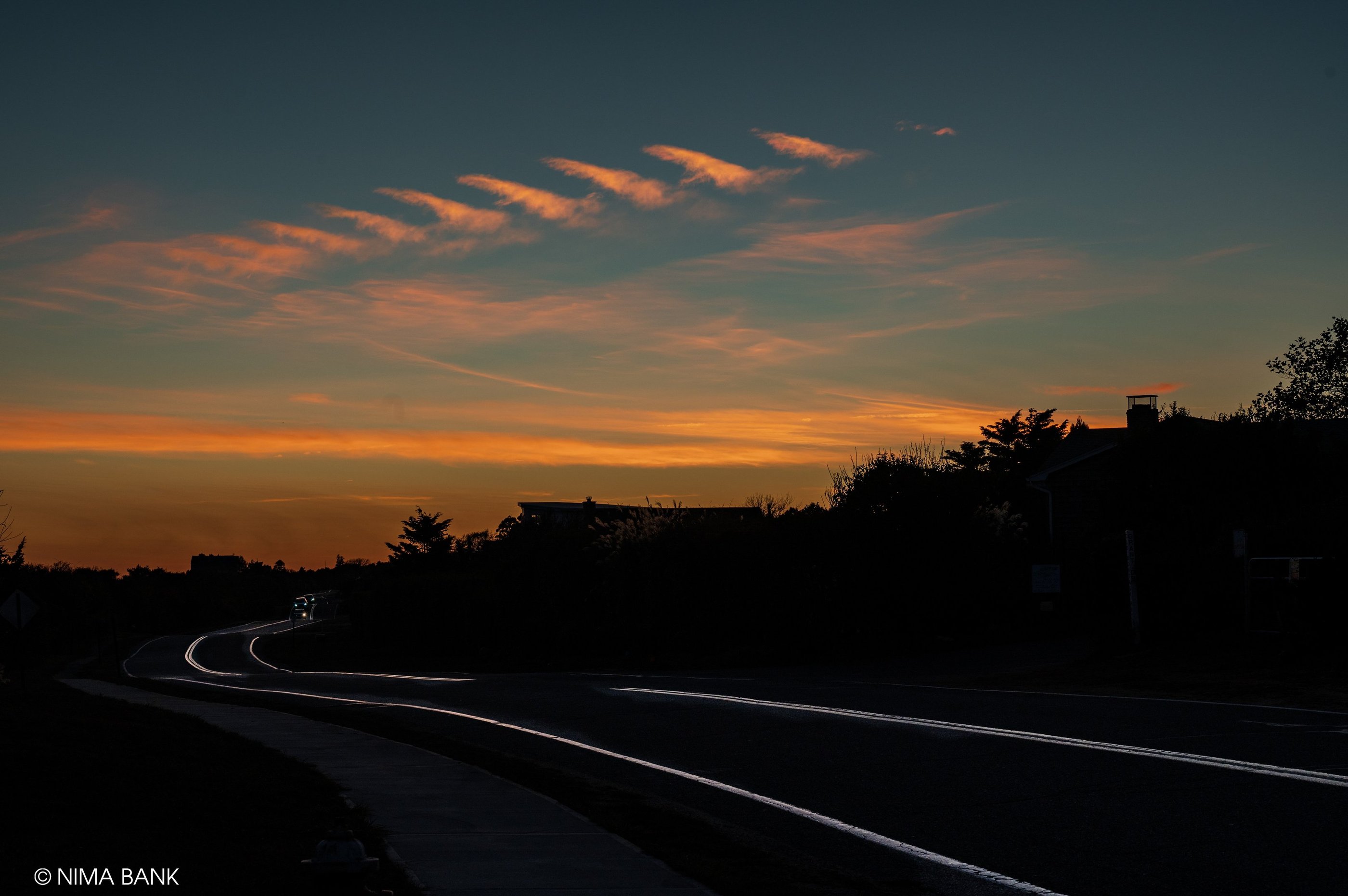 a  dark sunset scene of a road with a car on the horizon, old montauk highway